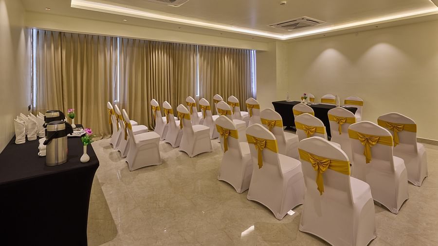 A banquet hall with ambient lighting, chairs covered in white cloth in front a table used by a speaker