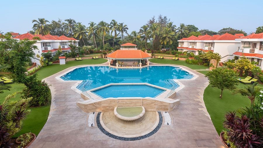 Symmetrical view of a pool with a gazebo and resort villas on either side.