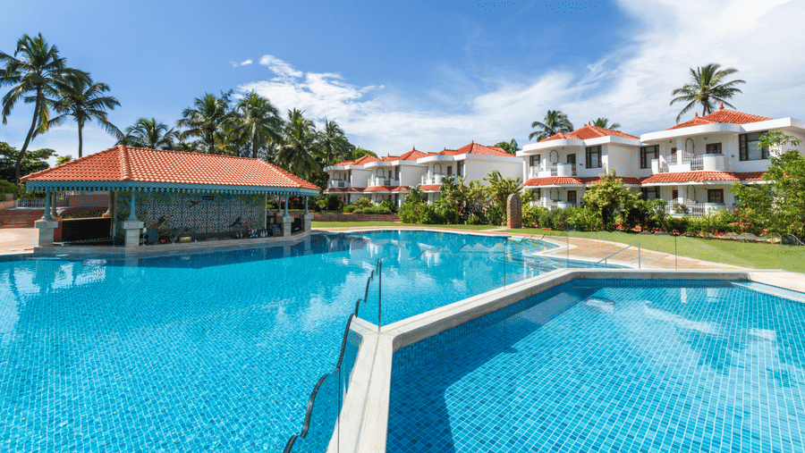 Spacious pool area with clear blue water and resort buildings in the background.