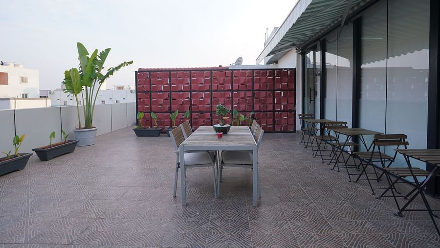 A rooftop dining space with a central table, chairs, and a decorative partition in the background at Hotel Kyzen Smartstays – Smart, Reliable, Kyzen