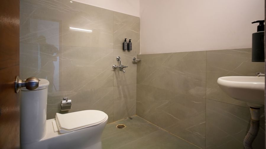 A clean, modern bathroom with a toilet, shower area, and sink, featuring tiled walls and a neutral colour palette - Beestay Hotels Financial District, Hyderabad 