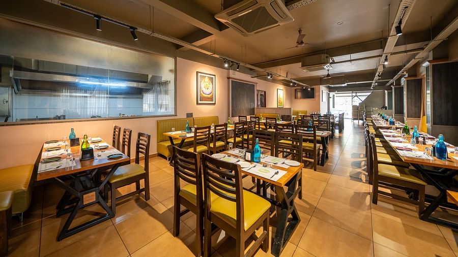 Image of a dining area with tables and chairs arranged around it at Hari Govindas, Siddappa Square.