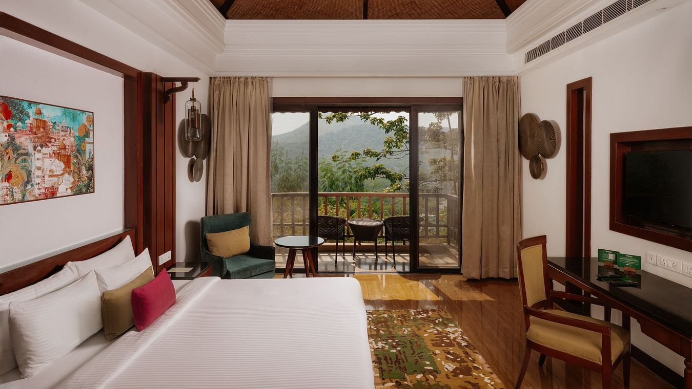 Side view of the Luxury Villa bedroom at The Ananta, Udaipur, featuring a spacious balcony with scenic views, and a flat-screen TV.