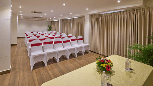 An image of a theatre style seating arrangement in our banquet hall with chairs covered in white cloth and red ribbons tied around the backrests - Grand Continent, Brookefield