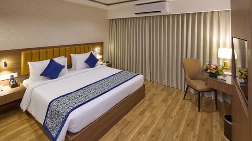 A spacious hotel room in Bengaluru featuring a king size bed, an AC, a work desk and warm accent lighting - Grand Continent, Brookefield