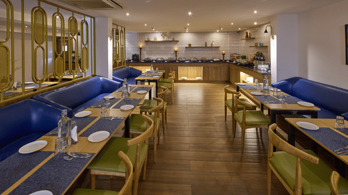 A chic dining area at our hotel with blue couches, glass tables, upholstered chairs and cosy lighting - Grand Continent, Brookefield