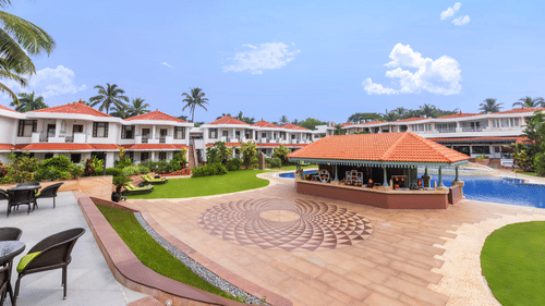 Curved poolside walkway with symmetrical design, set amidst a lush landscape at Heritage Village Resorts & Spa, Goa