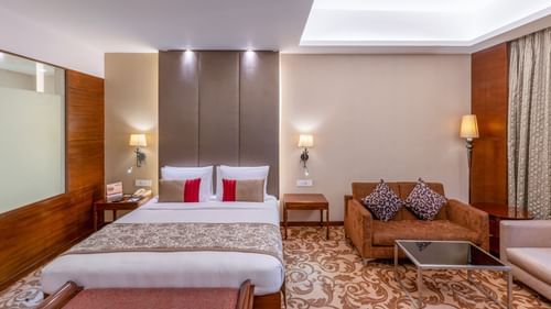 Bedroom of Presidential suite featuring a plush bed with fancy headboard next to a sofa set with a coffee table