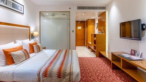 Superior room featuring a plush bed in front of a Tv mounted on the wall and a bathroom with frozen glass