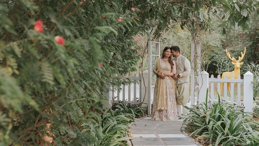 A couple posing for a picture with greenery around them - Karma Lakelands.