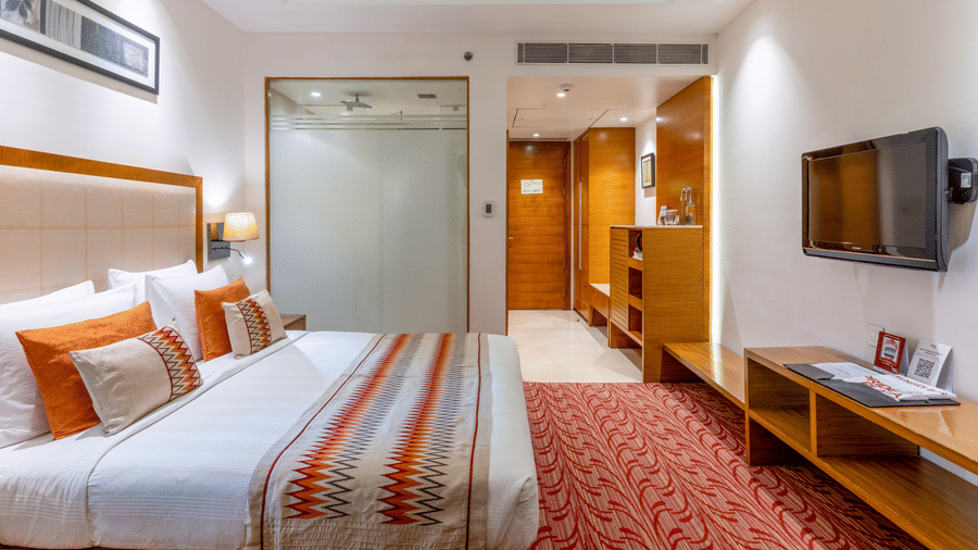 Superior room featuring a plush bed in front of a Tv mounted on the wall and a bathroom with frozen glass