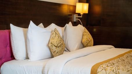 A luxurious hotel bed with plush pillows, gold-accented linens, and ambient lighting - Hotel Udai Median, Udaipur.