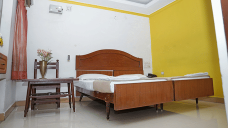 Low-angle view of a double bedroom at Hotel Vikram showing the ceiling fan and minimalist decor.