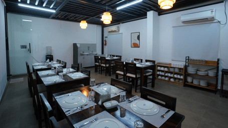 A rooftop dining area with tables and chairs, partially shaded, overlooking a bright outdoor space at Hotel Kyzen Smartstays – Smart, Reliable, Kyzen