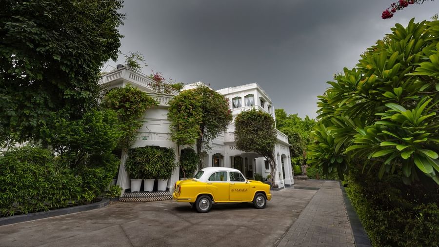 A yellow car parked on the front porch of Saraca Hotel, Lucknow on a cloudy day