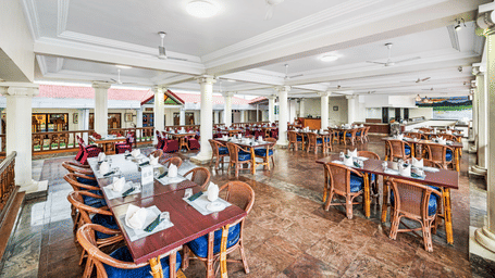 An image of the outdoor dining area at Dhanyam restaurant featuring tables and chair at GReaT Trails River View Resort Thanjavur By GRT Hotels