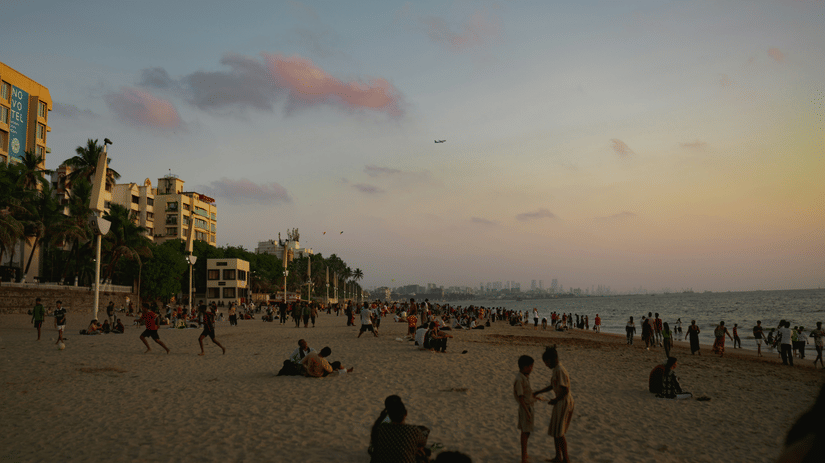 A view of people moving about on the sand of Juhu Beach.