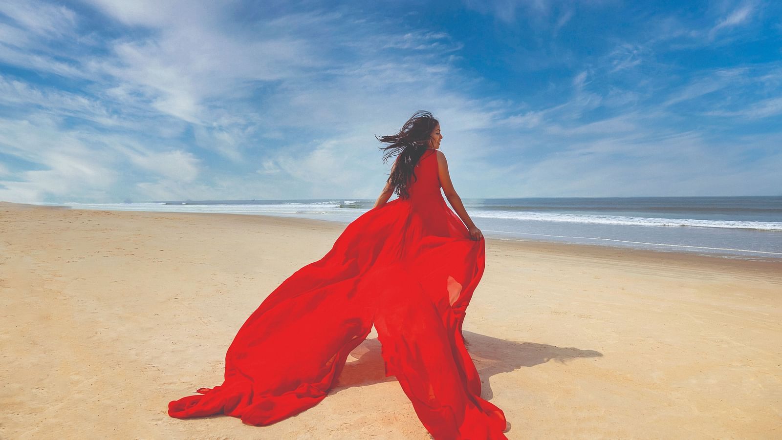 a woman with a long red dress running on the beach - Caravela Beach Resort Goa.