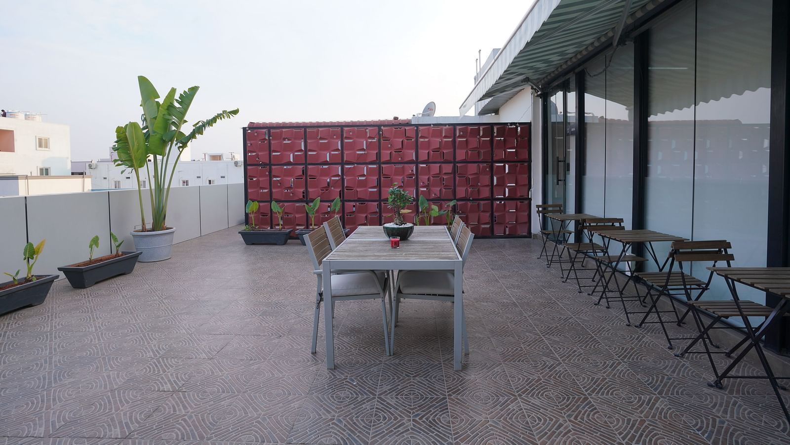 A rooftop dining space with a central table, chairs, and a decorative partition in the background at Kyzen Smart Stays.