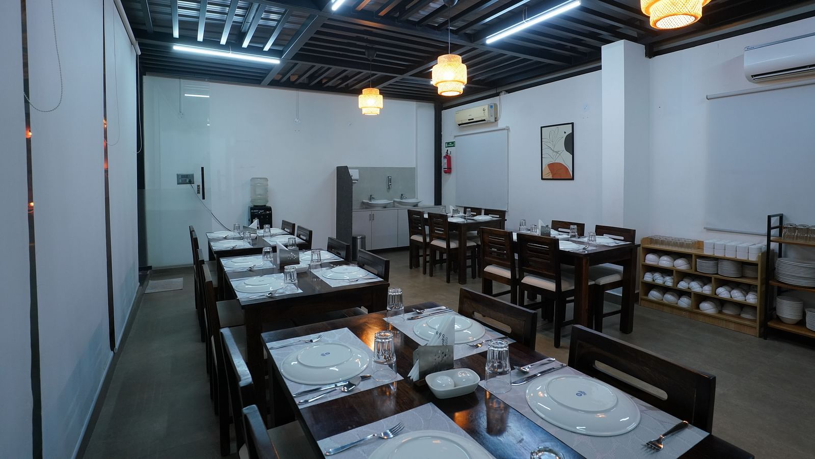 A rooftop dining area with tables and chairs, partially shaded, overlooking a bright outdoor space at Kyzen Smart Stays.