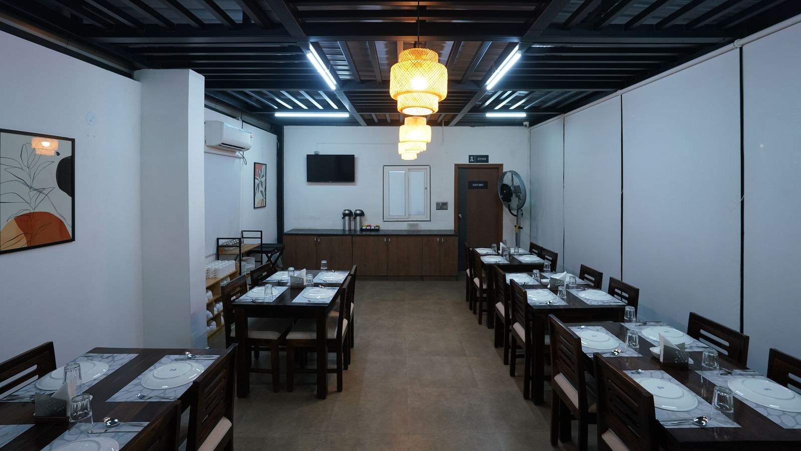 view of the indoor dining area, showing more tables and chairs in a well-lit, minimalist setting at Hotel Kyzen Smartstays – Smart, Reliable, Kyzen
