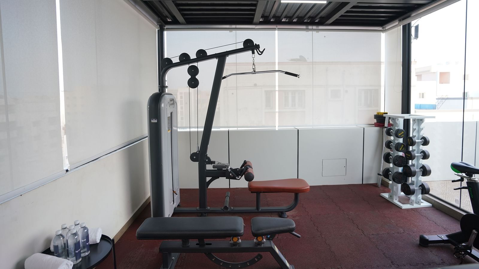 A fully equipped gym with workout benches, a lat pulldown machine, and weights at Kyzen Smart Stays.