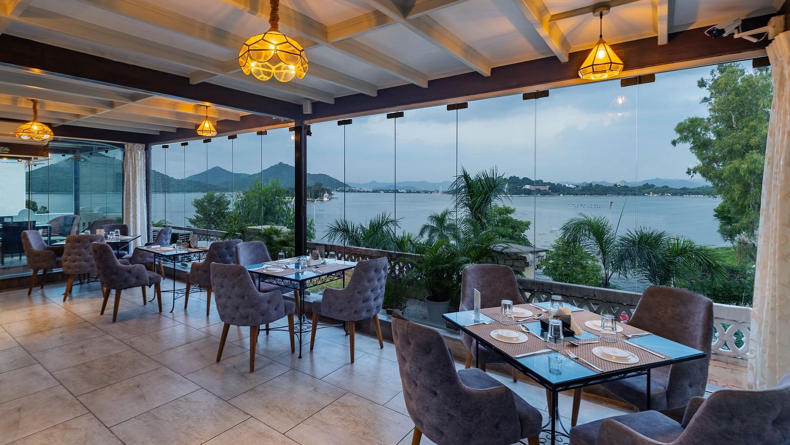 Restaurant area at Panna Vilas Palace includes a four-seater table surrounded by wooden chairs, complemented by warm lighting and potted plants | Panna Vilas Udaipur