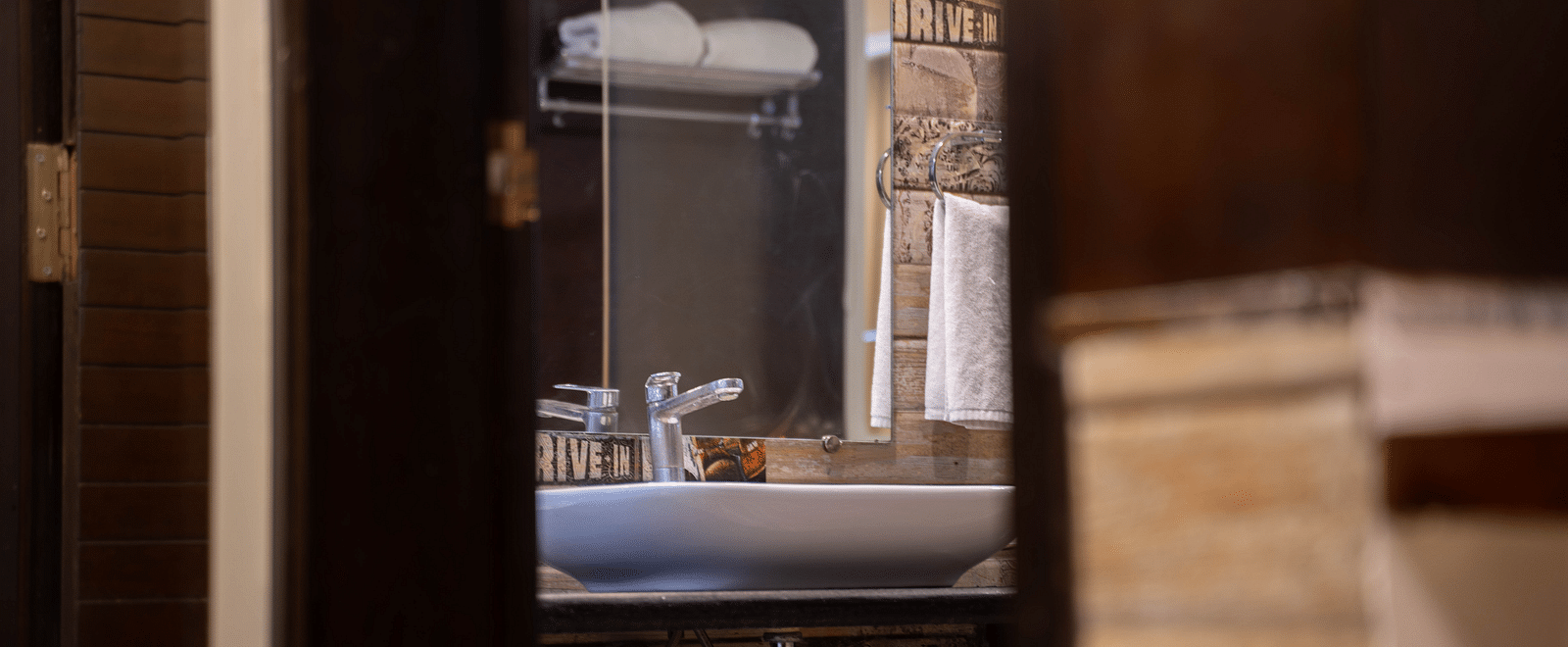 A bathroom view with a sleek vanity mirror, glass shower, and warm lighting - Hotel Udai Median, Udaipur.