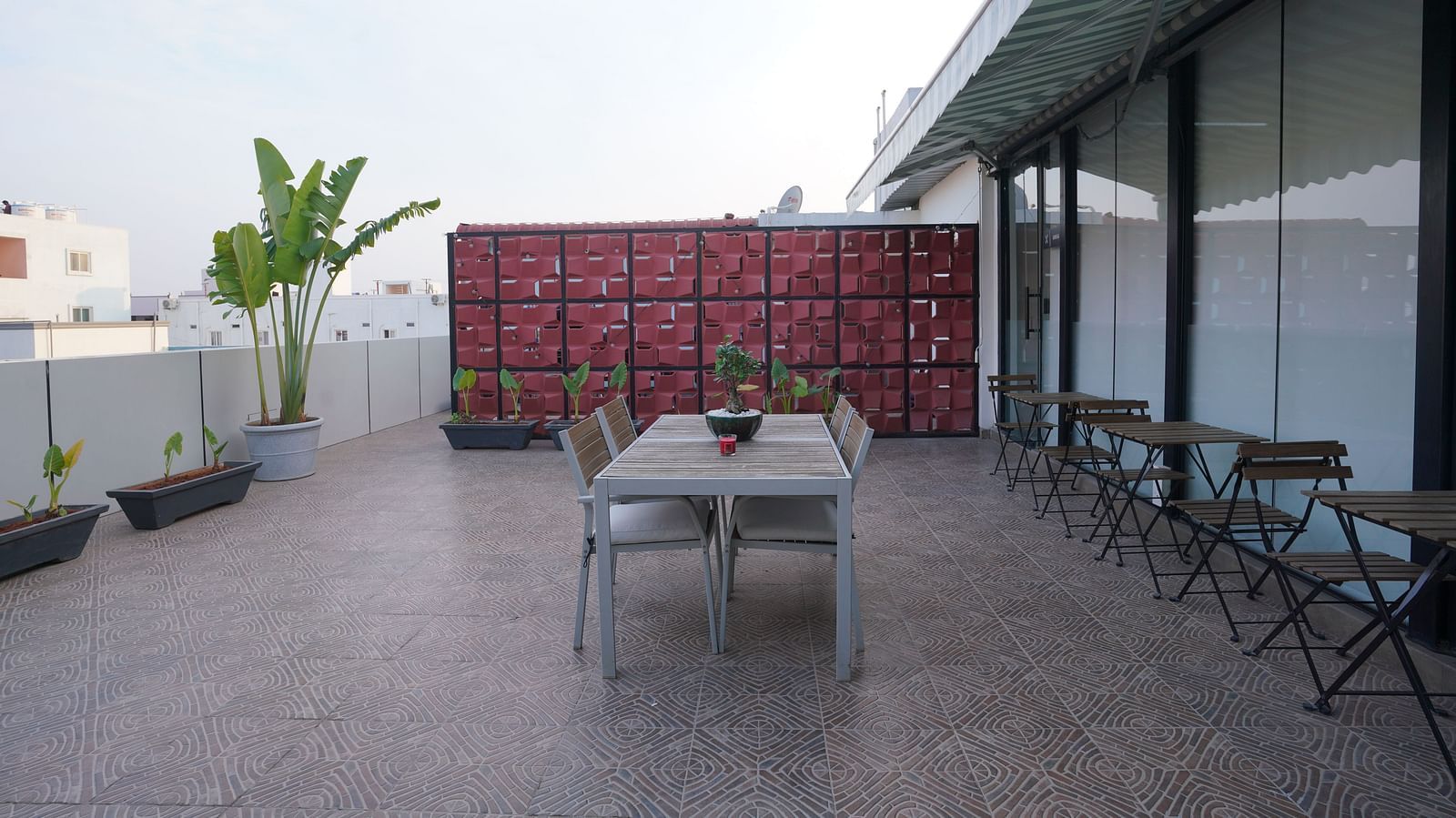 A rooftop dining space with a central table, chairs, and a decorative partition in the background at Hotel Kyzen Smartstays – Smart, Reliable, Kyzen