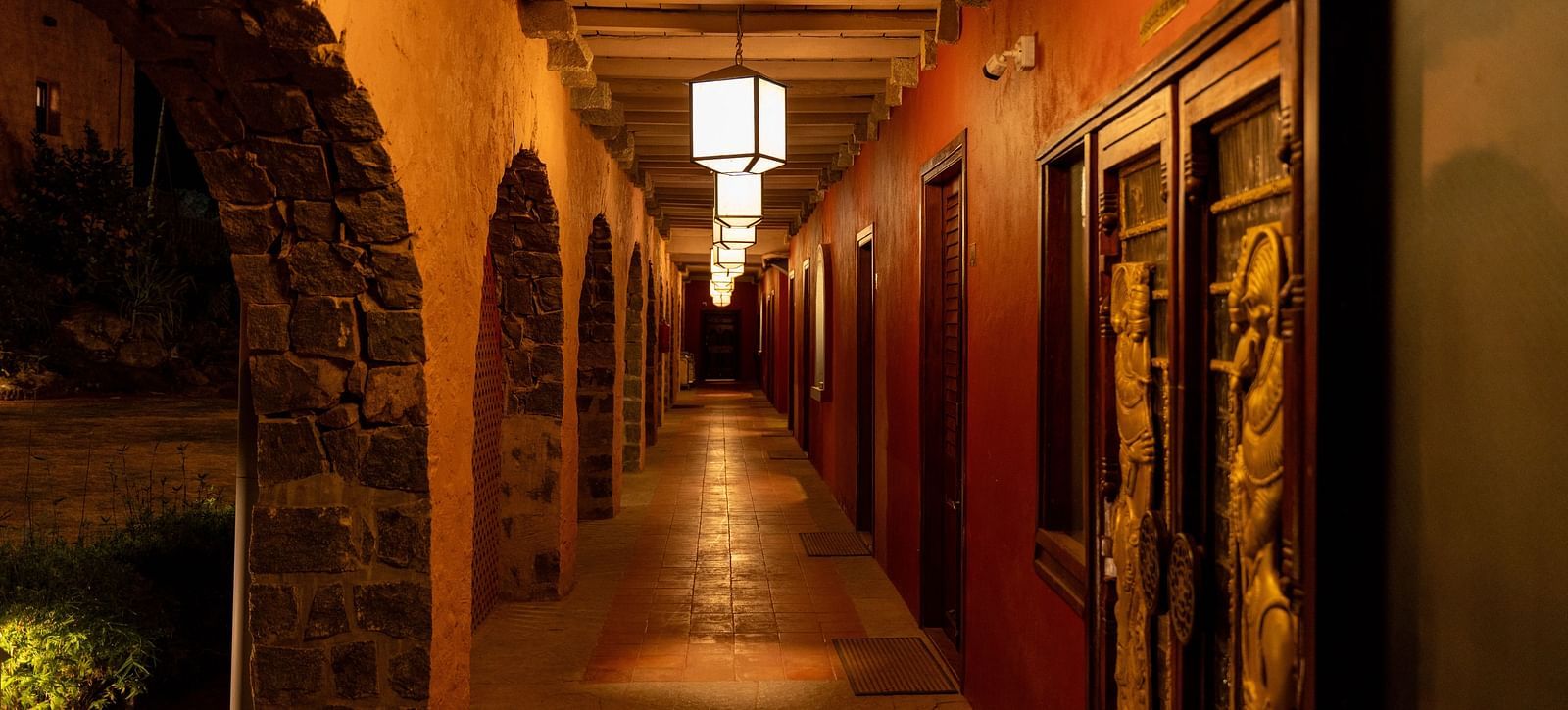 Well-lit corridor with stone arches and warm lighting in a hotel | Mango Hill, Yercaud