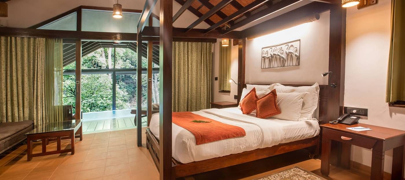 Room with a double bed, wooden accents, and forest views at Vythiri Resort, Wayanad