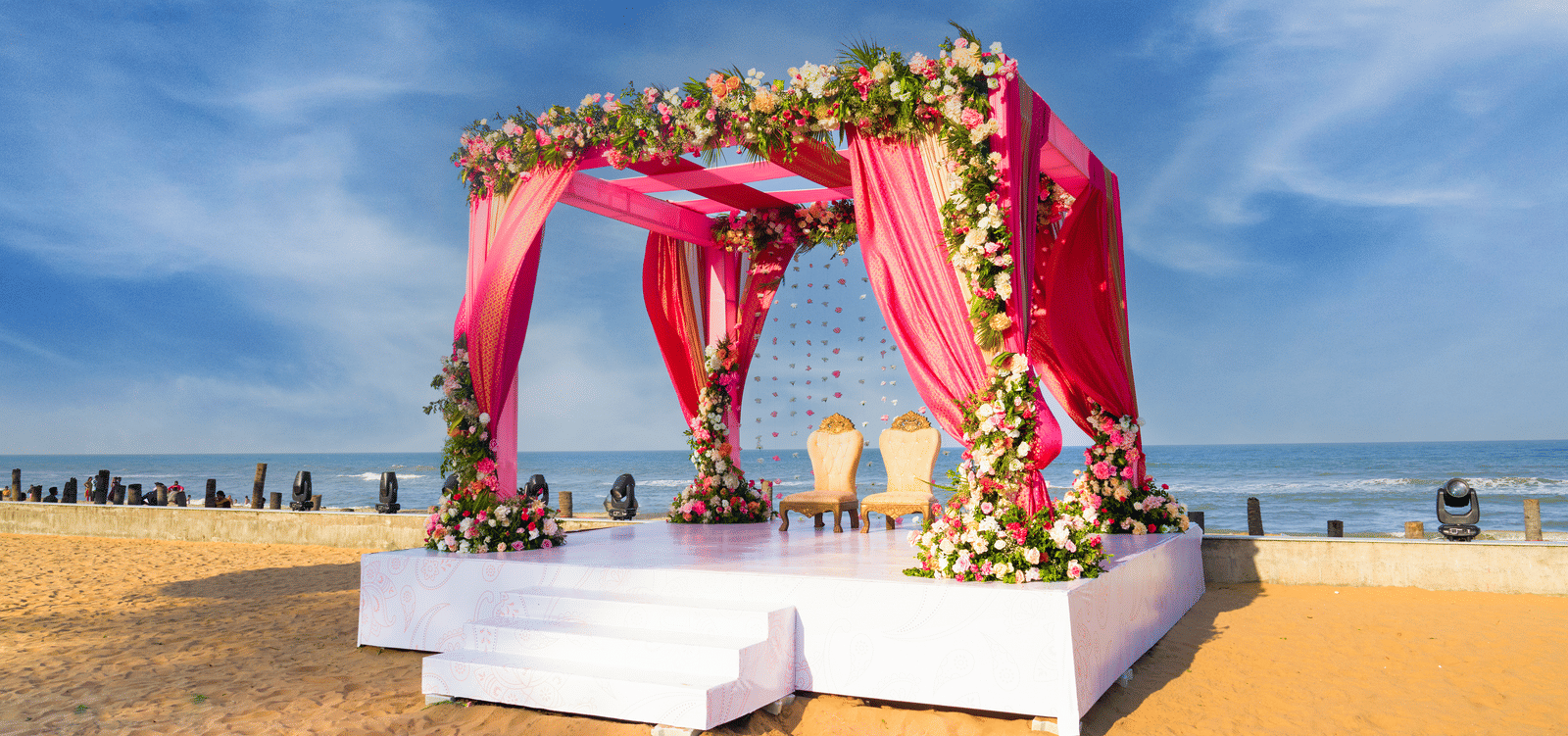 Pink floral mandap setup on the beach with draped fabric and white platform - Grande Bay Resort & Spa, Mamallapuram