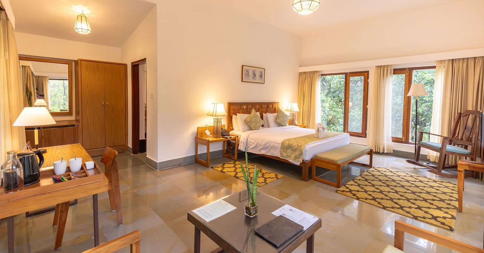 Premium Suite at Saraca Resort & Spa Corbett with a double bed, a sofa chair, a work desk and chair and a chandelier