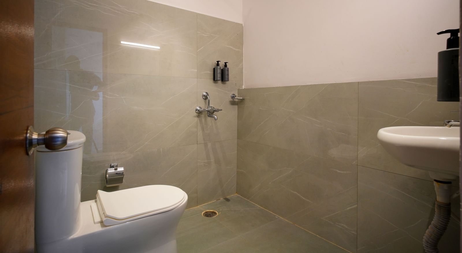 A clean, modern bathroom with a toilet, shower area, and sink, featuring tiled walls and a neutral colour palette - Beestay Hotels Financial District, Hyderabad 