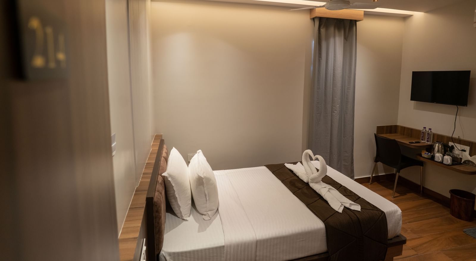 Double bed with curtains, wall-mounted TV, and cosy atmosphere at Beestay Hotels, Rajahmundry.