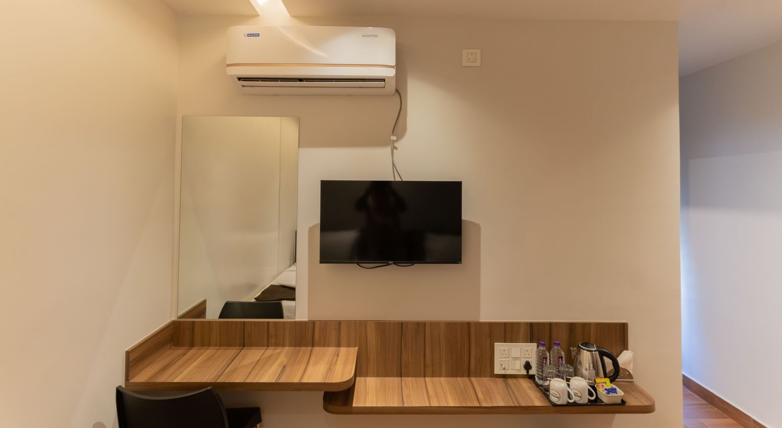 Bedroom view with a desk, wall-mounted TV, and air-conditioning at Beestay Hotels, Rajahmundry.