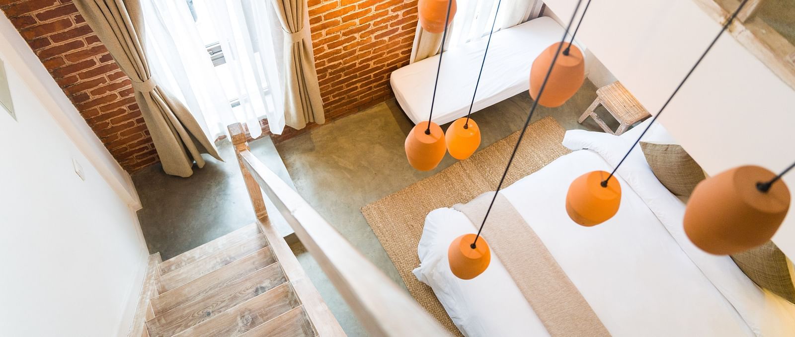 An aerial shot of the deluxe loft room with a staircase and chandelier hanging above it - The Nanee