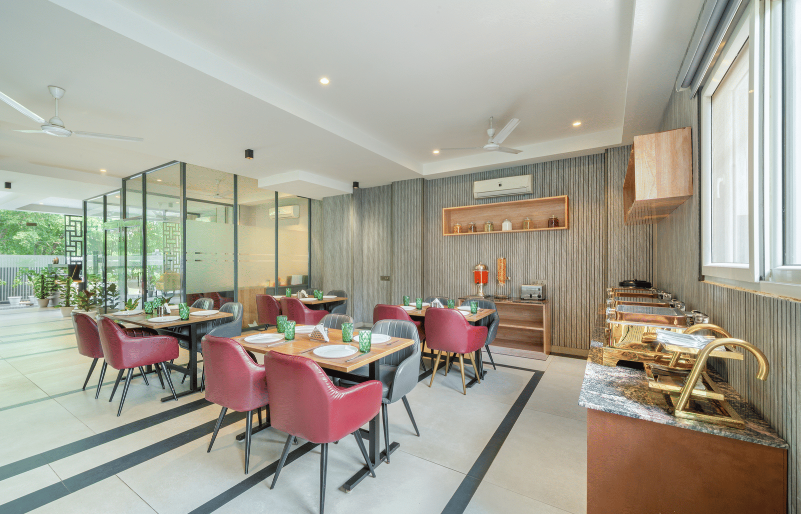 Bright dining area with neatly arranged tables, cushioned chairs, and buffet setup by the window at Lime Tree Hotel & Stays Greater Noida Nearby India Expo Centre & Mart.