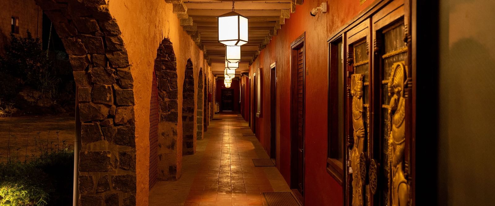 Well-lit corridor with stone arches and warm lighting in a hotel | Mango Hill, Yercaud