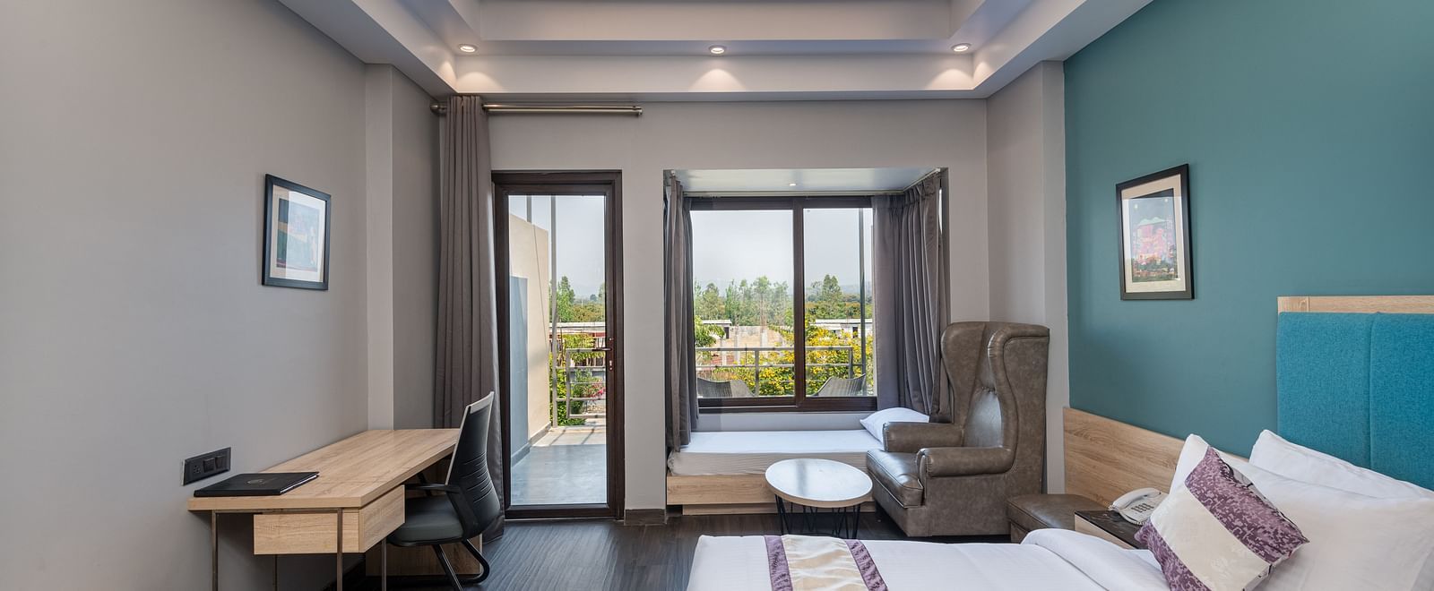 Well-lit bedroom with double bed, sitting area and balcony access - DLS Forest Vines Resort & Spa, Ramnagar (Jim Corbett)