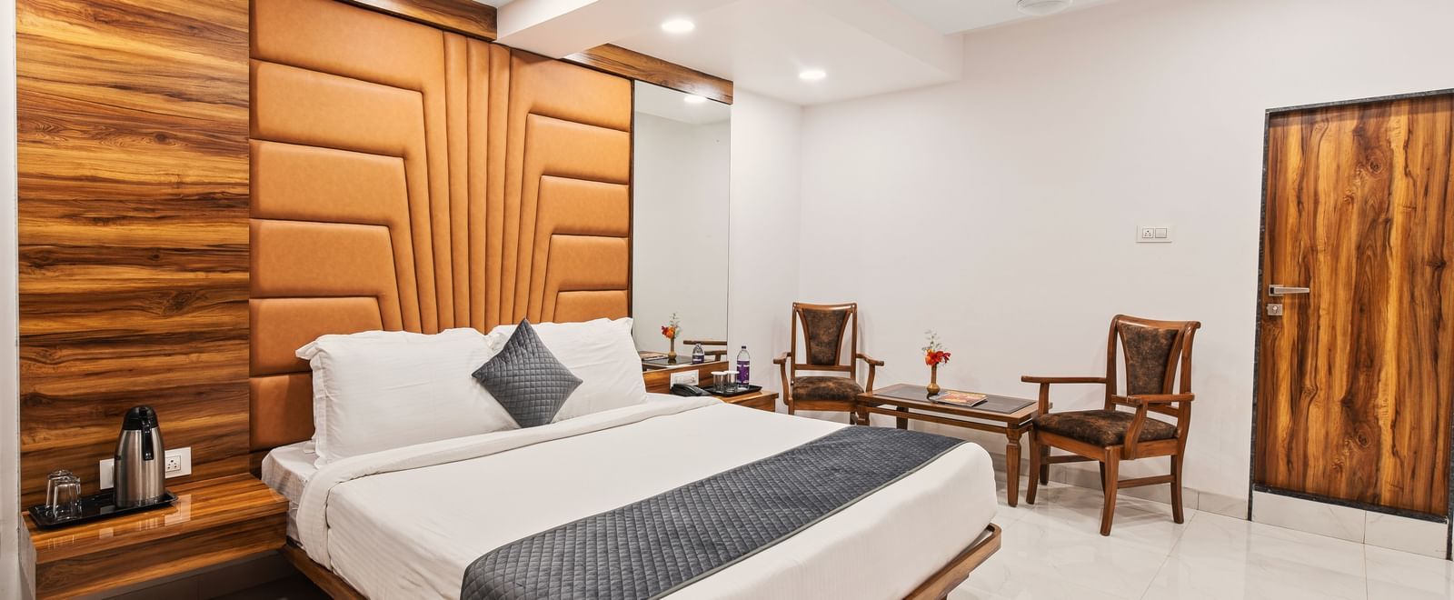 Spacious bedroom at Mayur Retreat featuring a king-size bed, dining table, and modern wooden furnishings.
