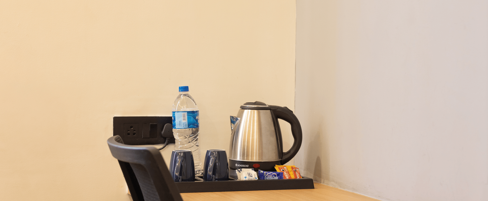 Interior of a guest room showing the desk area with a kettle and refreshment supplies at Pravasa Stay Luv Kush, Indore.