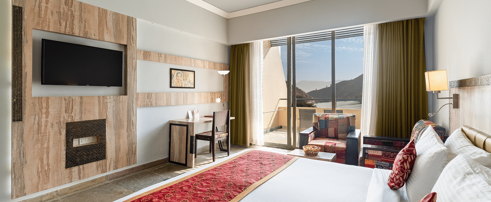 A close-up shot of a bed, opposite to it is a tv mounted on the wall - Via Lakhela Resort & Spa