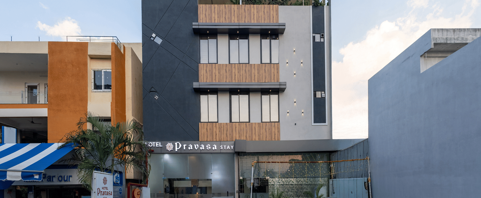 The facade of a modern multi-storey Pravasa Stay Dewas Naka, Indore under the blue sky.
