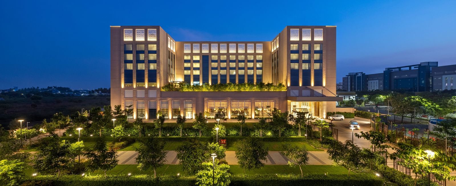 A striking twilight aerial perspective of the hotel, surrounded by manicured lawns - Grand Madurai by GRT Hotels