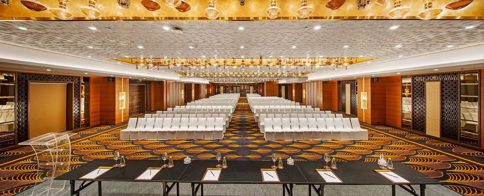 Banquet hall featuring a luxurious golden ceiling and rows of white chairs at Radisson BLU