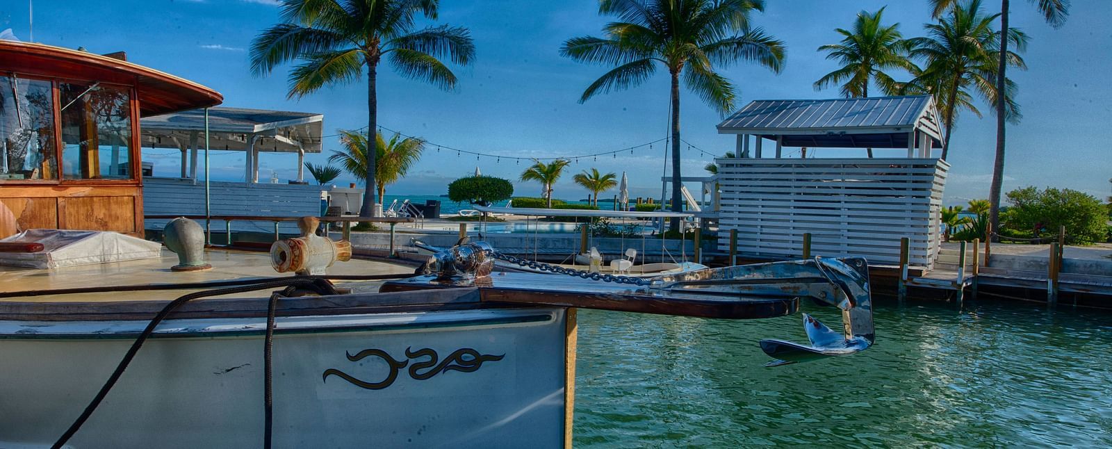 View of Casa Morada's waterfront with a docked boat, palm trees, and resort buildings in the background.