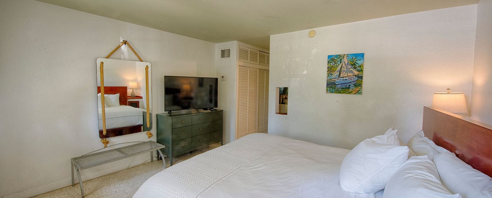 White bed in a Casa Morada suite with a mirror, open floor space, and subtle lighting.