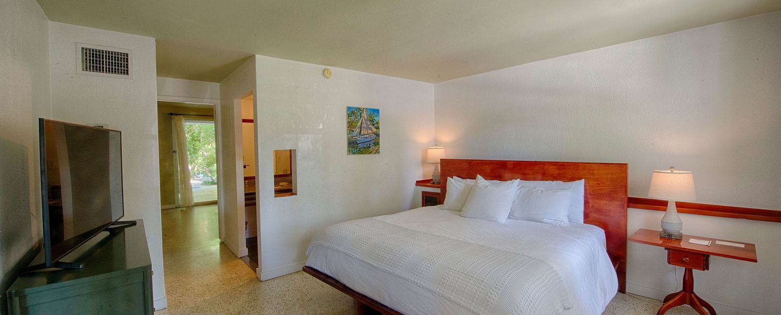 Casa Morada's bedroom with a king bed, wooden headboard, wall art, and a TV.