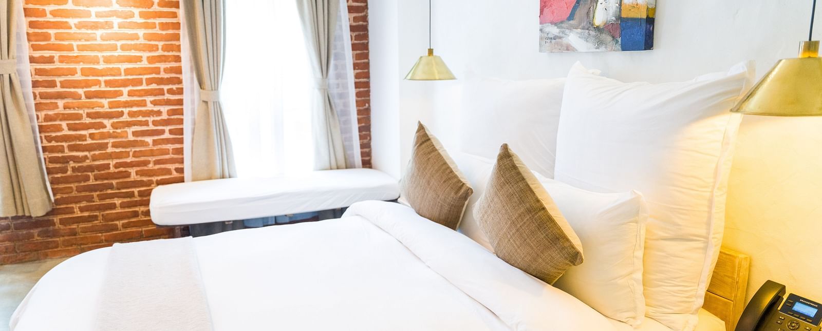 The deluxe loft room with a bed, bed side table, with a telephone places on it, and lamps - The Nanee